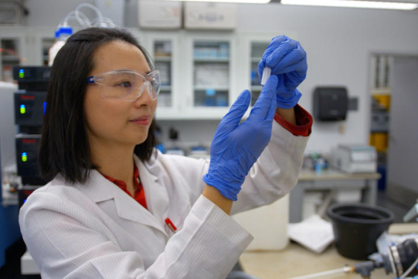 scientist in white coat looking at vial
