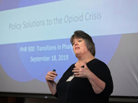 professor standing in front of slide that reads:  Policy Solutions to the Opioid Crisis