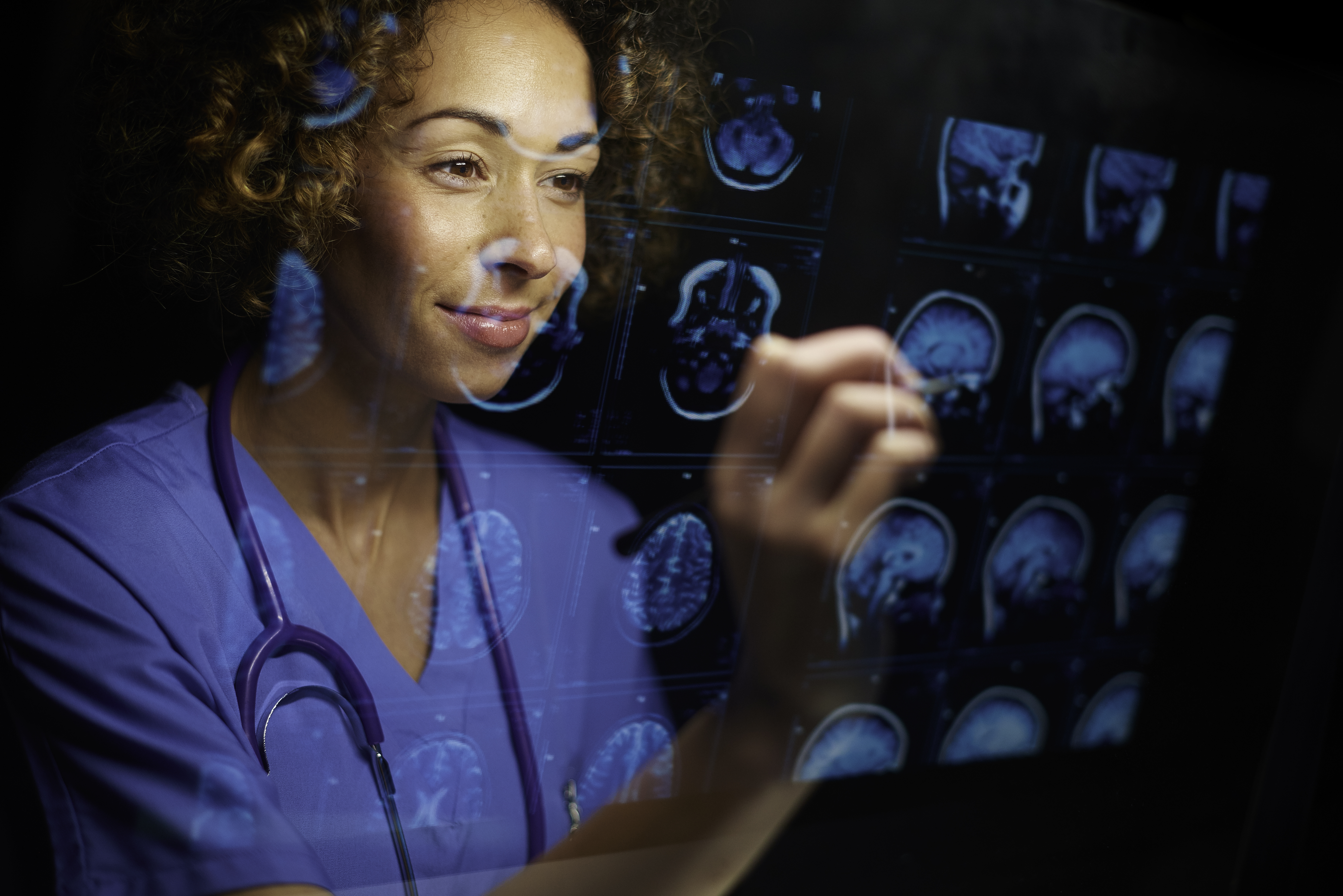 person in scrubs looking at brain scans