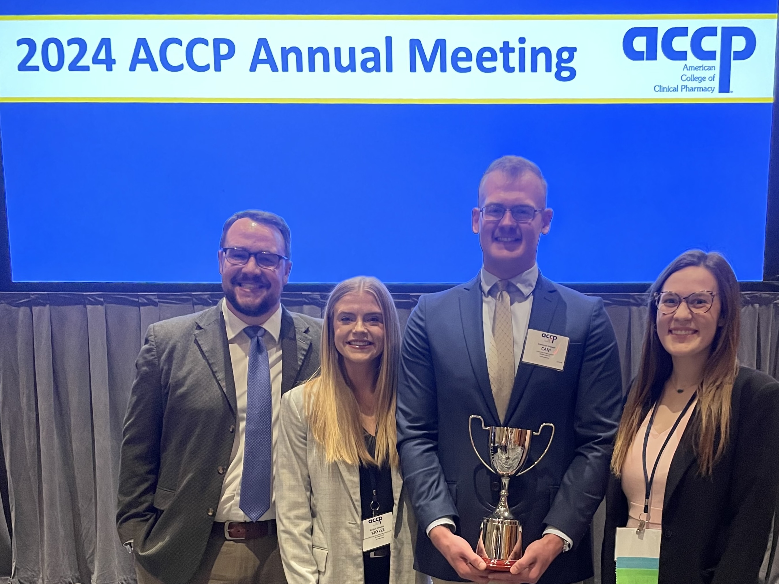 group of four people smiling and holding a trophy