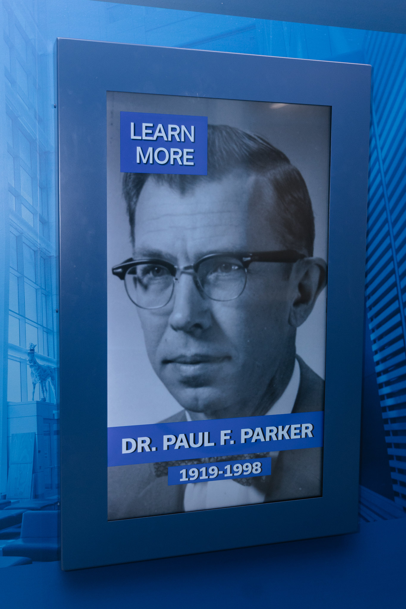 A touch screen showing the headshot of Paul F. Parker with a button that says "learn more"