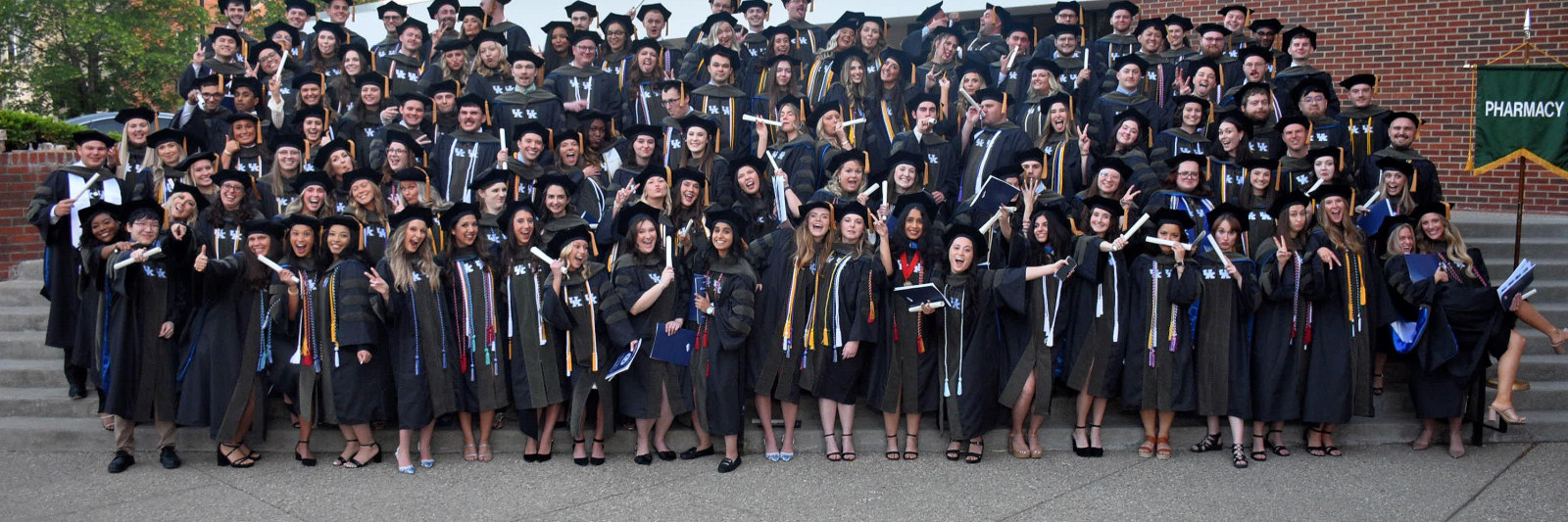 A group of graduates pose outdoors on stairs
