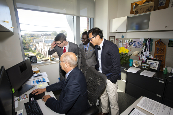 faculty member and three students looking at a computer
