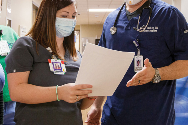 man and woman in scrubs and PPE looking at a piece of paper