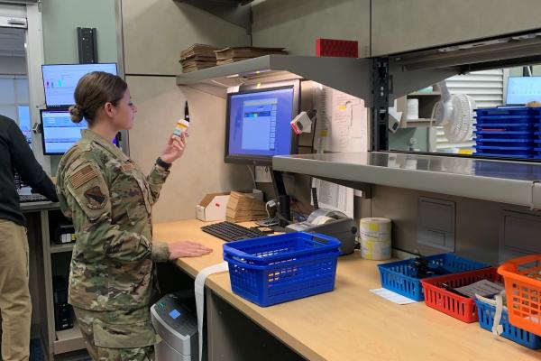 woman standing in camo looking at medication bottle