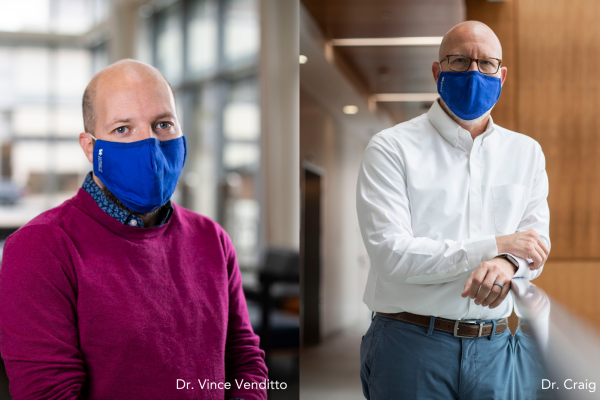 two men standing wearing blue face masks