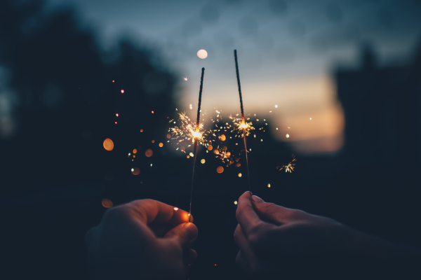 two hands holding sparklers that are lit
