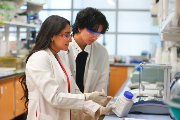 inside a lab, two people look at a label on a bottle