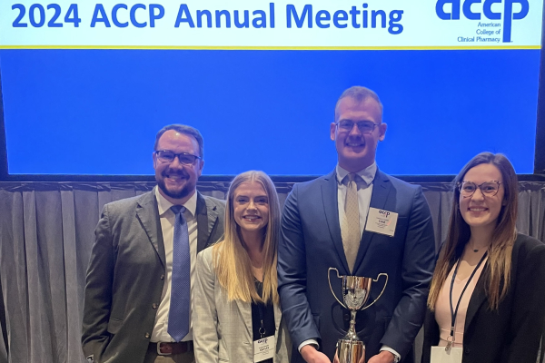 group of four people smiling and holding a trophy