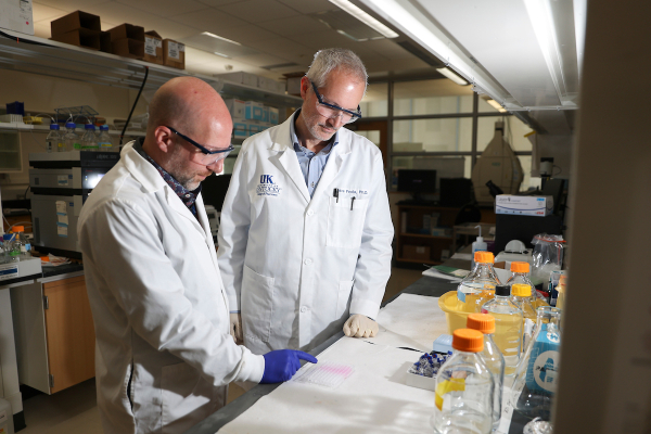 two men wearing white coats in a lab
