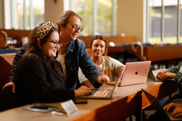 A professor pointing at a screen while two students watch