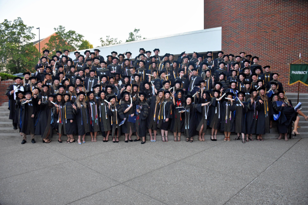 A group of graduates pose outdoors on stairs