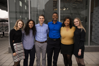 six students standing outside smiling in the snow