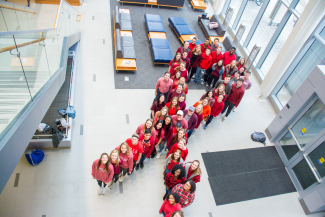 students dressed in red standing in shape of ribbon