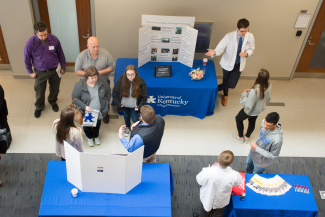 students standing at tables talking to people