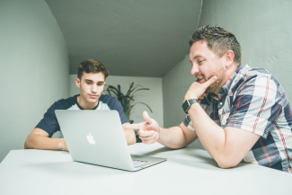 two men facing a laptop at a table