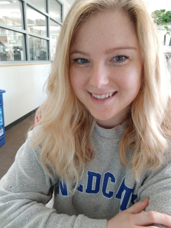 Photo of Kaitlind Howard smiling and wearing a grey sweater that says Wildcat in blue lettering