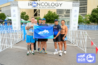 group of men posing with college of pharmacy flag at finish line