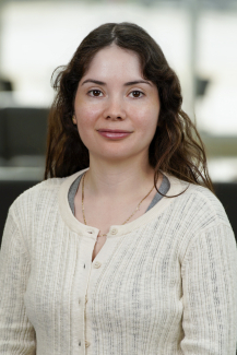 woman with dark hair wearing a beige cardigan smiling softly