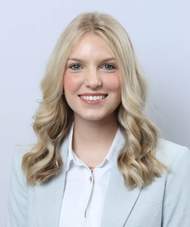 a blonde woman in professional attire against a neutral backdrop