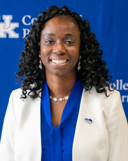 woman wearing blue and white suite jacket smiles in front of blue backdrop