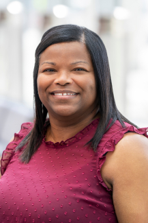 a woman wearing a berry colored shirt smiling in a brightly lit setting
