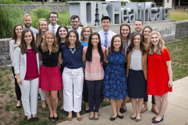 group of residents in business professional clothes smiling while standing outside