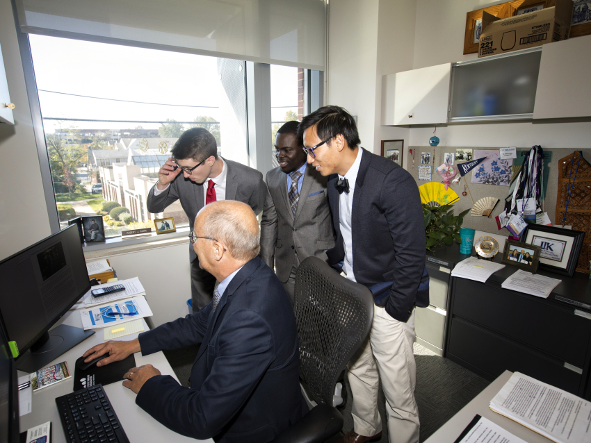 faculty member and three students looking at a computer