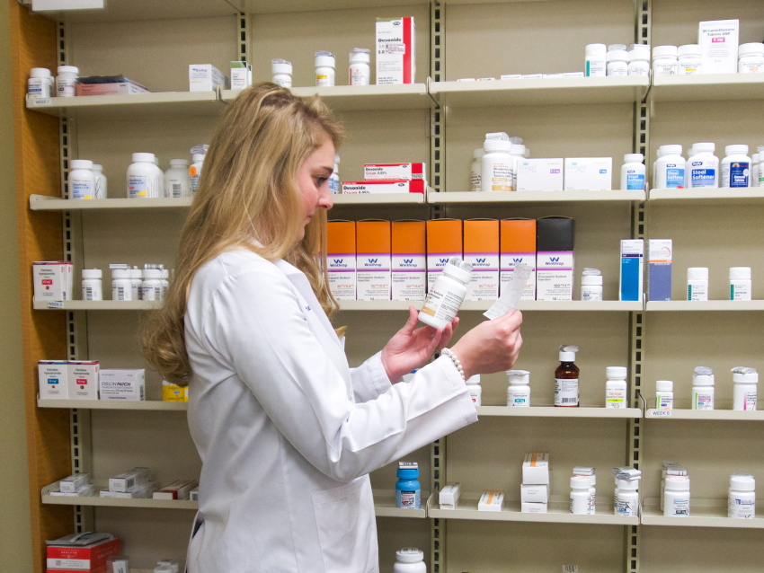 resident pharmacist looking at pill bottle with screipt