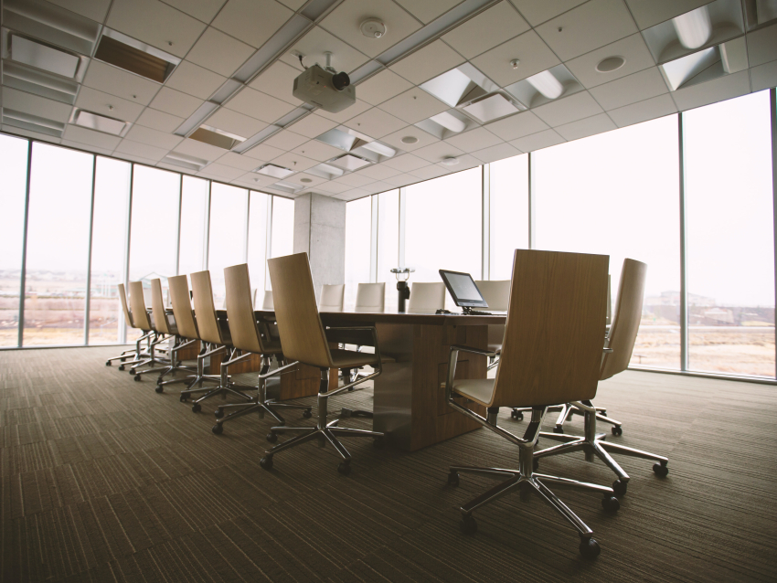 Minimalist boardroom with large table surrounded by empty chairs