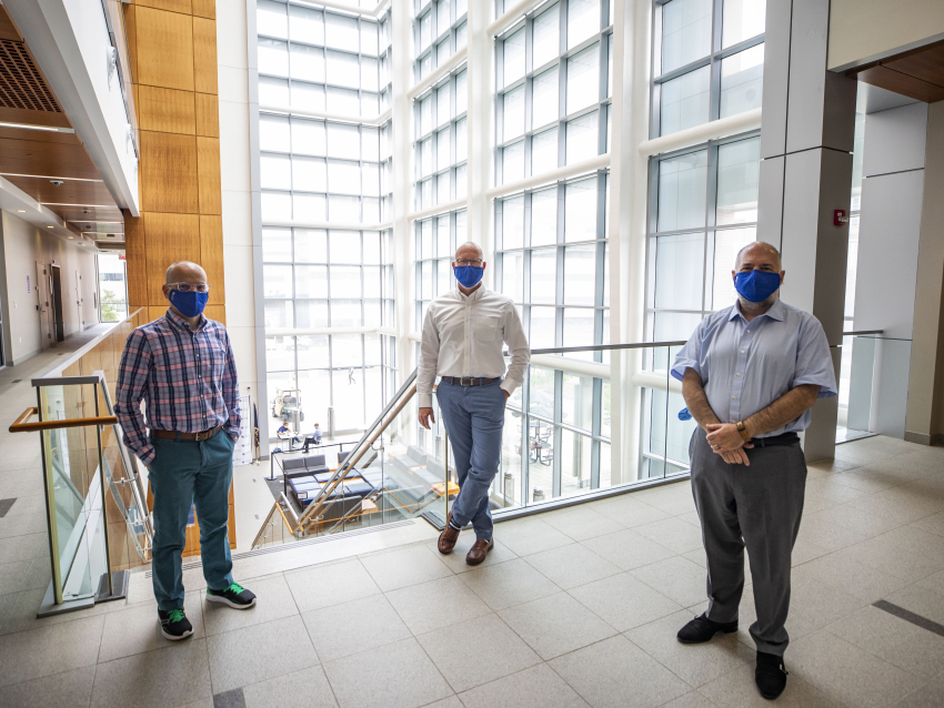 three people standing physically distant wearing masks