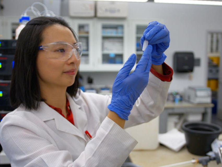 scientist in white coat looking at vial