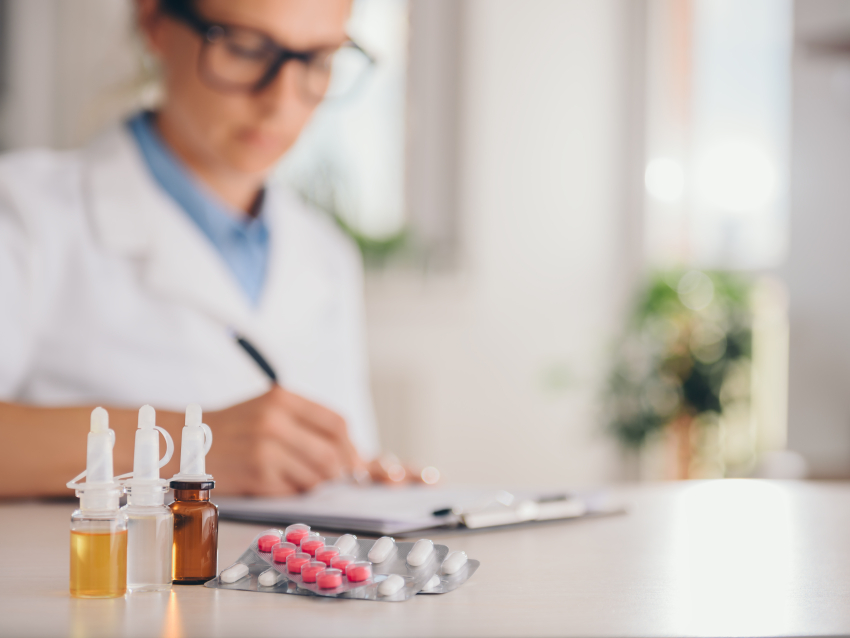 person in glasses writing on clipboard near medication