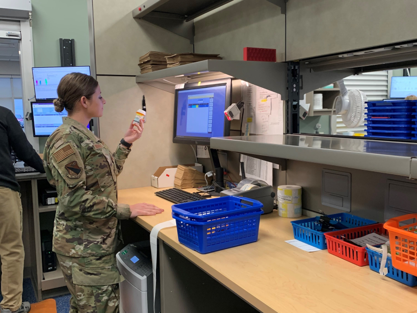 woman standing in camo looking at medication bottle