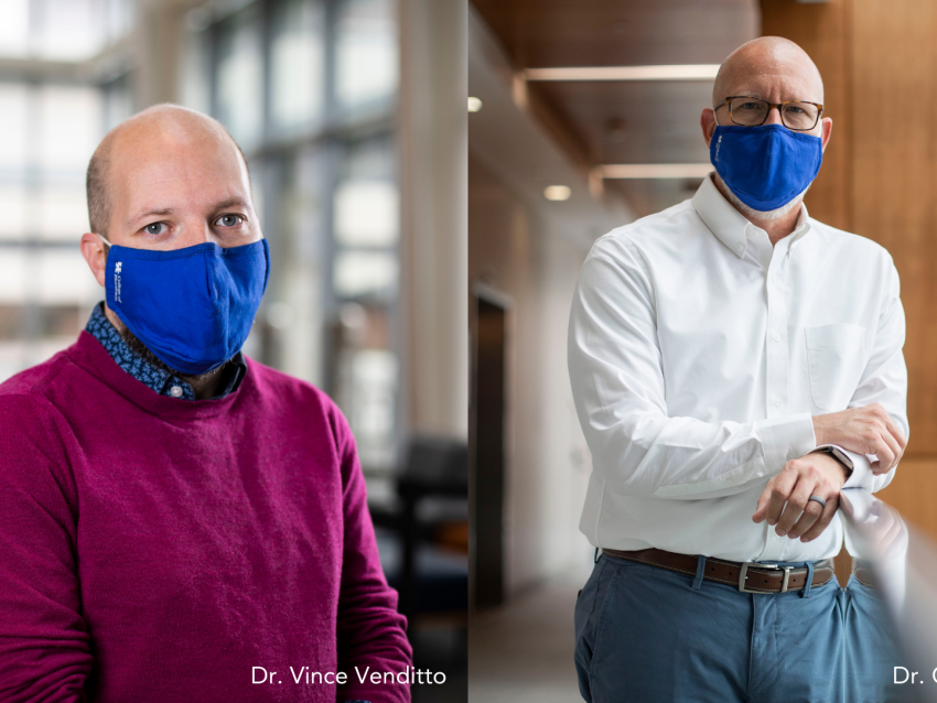 two men standing wearing blue face masks