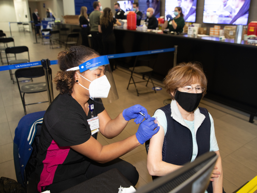 71 year old Gale Bhattacharyya, receives the Covid-19 vaccine from Tamyah Pipkin at Kroger Field at the University of Kentucky