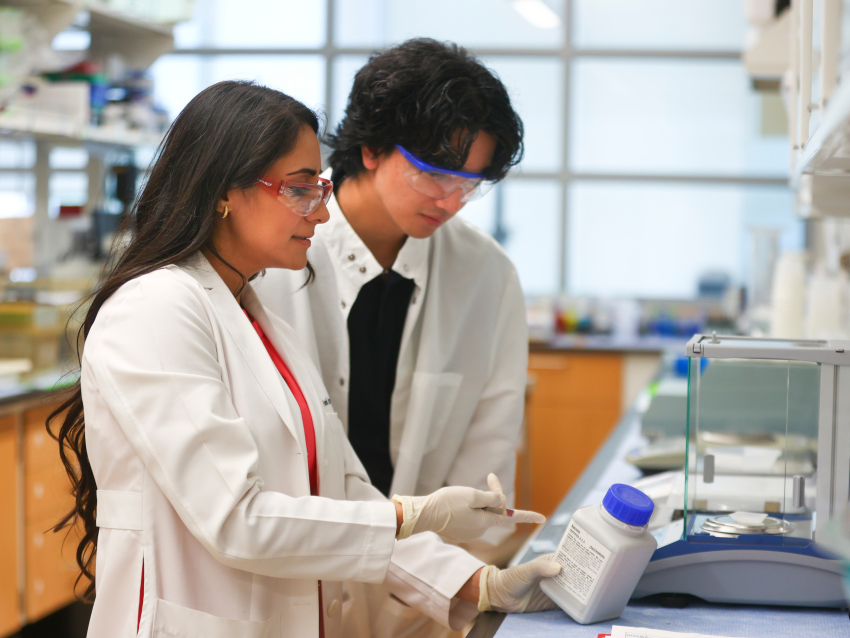 inside a lab, two people look at a label on a bottle