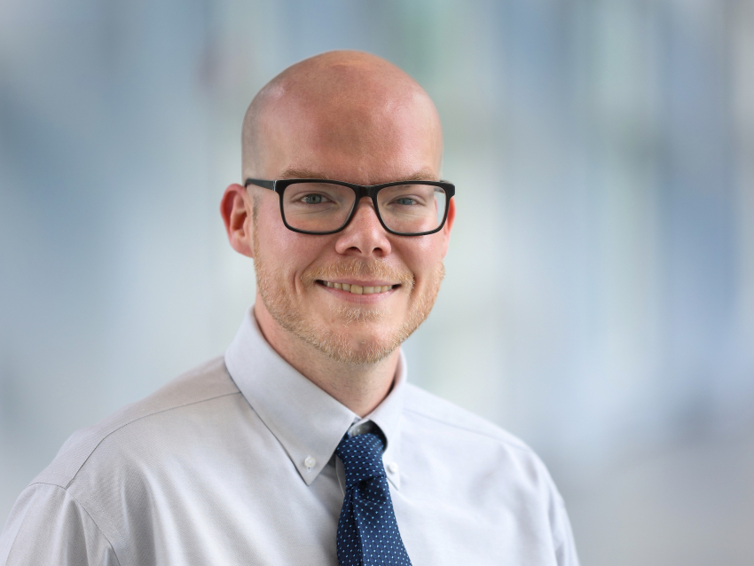 Man wearing glasses and a tie smiling