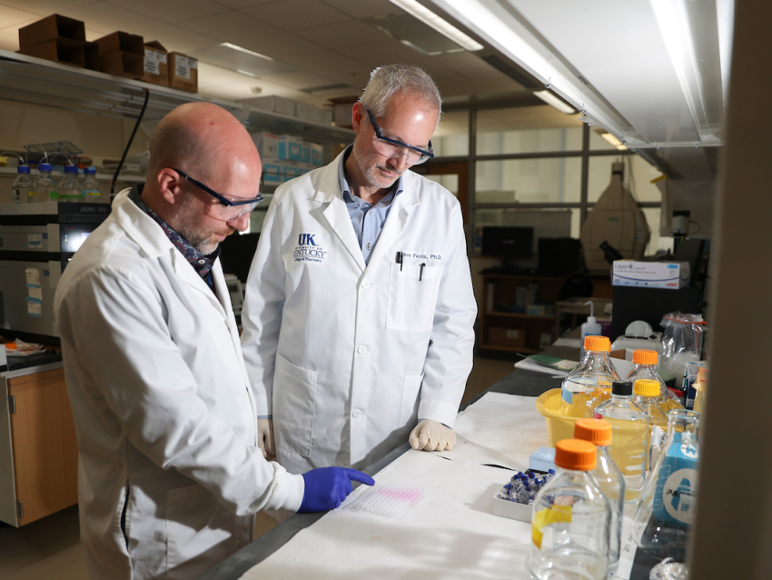 two men wearing white coats in a lab