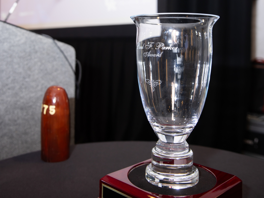 A photo of a glass award on a wooden stand next to a podium