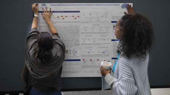 Grad Students Handing Research Poster