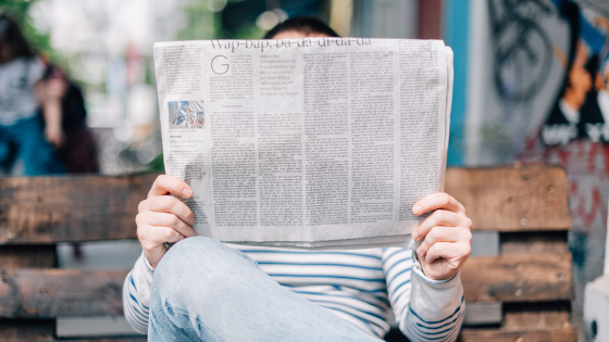 person sitting holding a newspaper