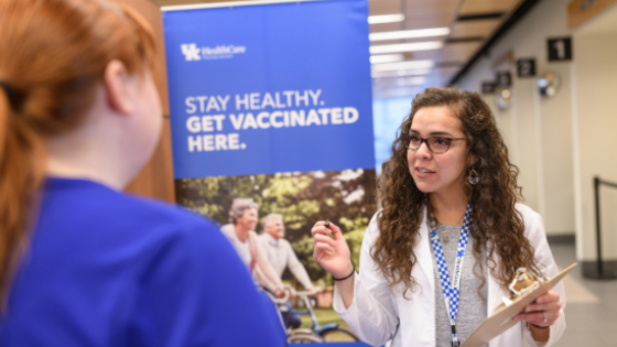 student with clipboard talking about vaccinations