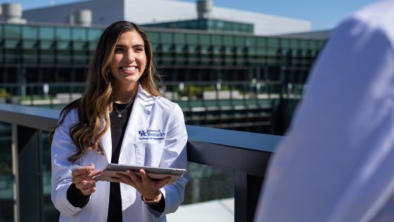 woman in white coat holding iPad