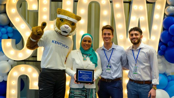 Dr. Helmy holding award with students and UK Wildcat