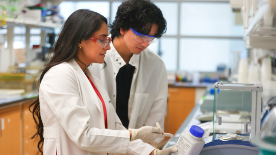 inside a lab, two people look at a label on a bottle