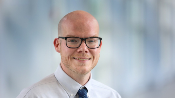 Man wearing glasses and a tie smiling