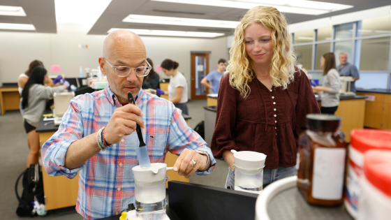 student watching professor conduct a science experiement