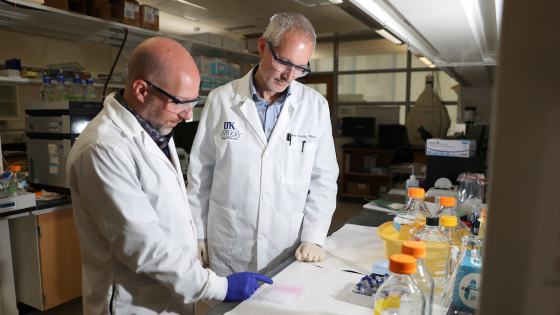 two men wearing white coats in a lab
