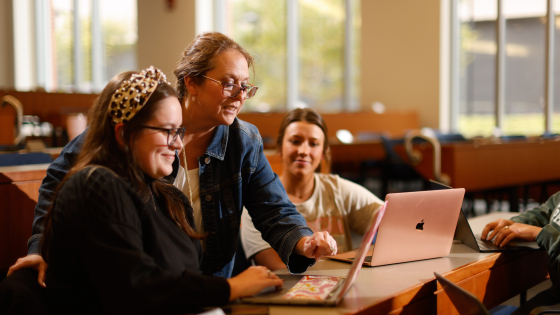 A professor pointing at a screen while two students watch